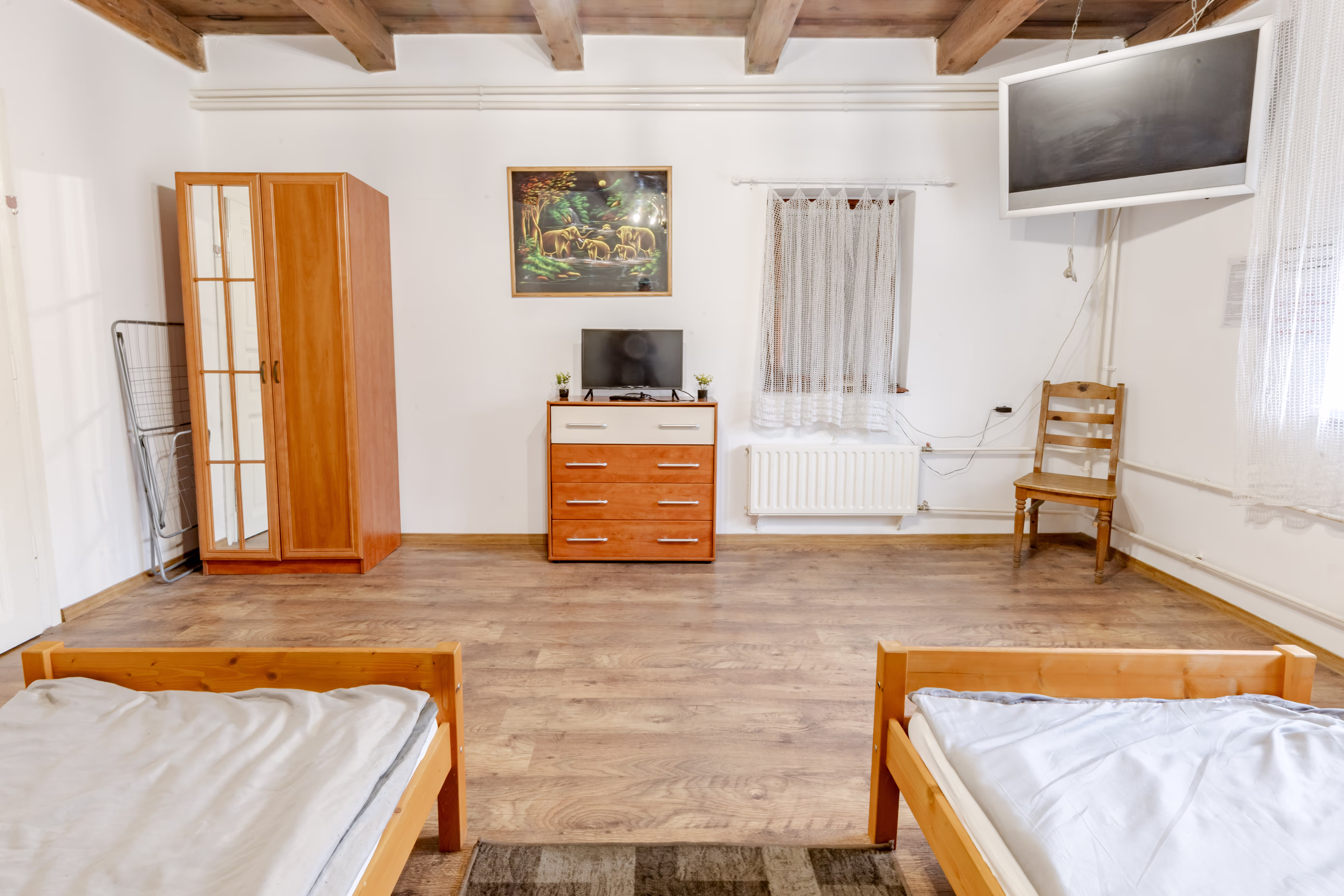 Berendezett hálószoba fenyőágyakkal, komóddal, TV-vel és fagerendás mennyezettel